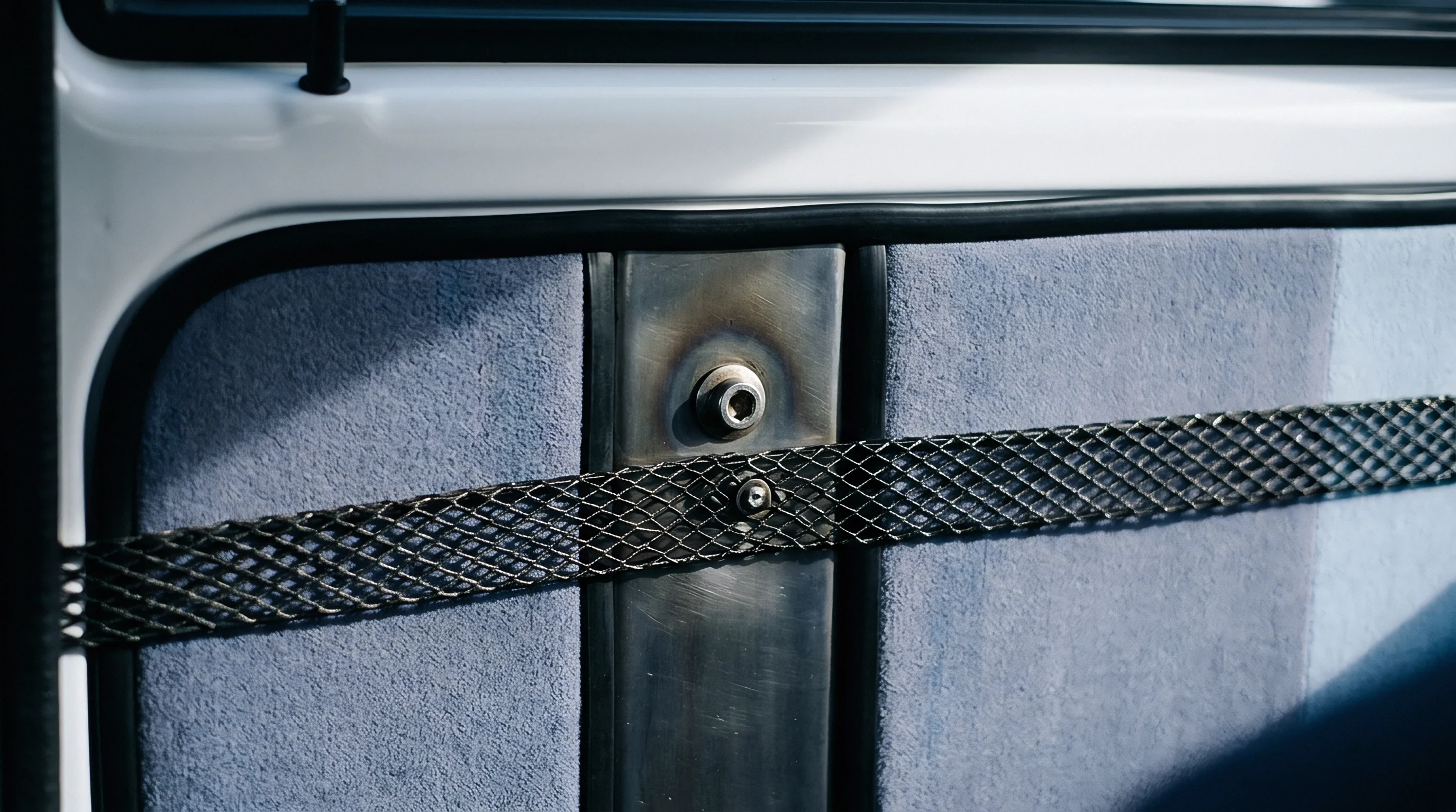 Textured fabric panels flank a secured central metal pillar featuring threaded fasteners inside a finished vehicle cabin.