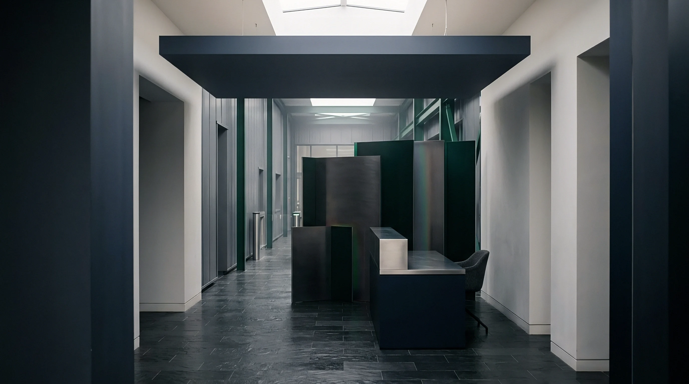 A dark metallic reception desk sits below a floating ceiling panel within a stark industrial building corridor featuring stone flooring and white walls.