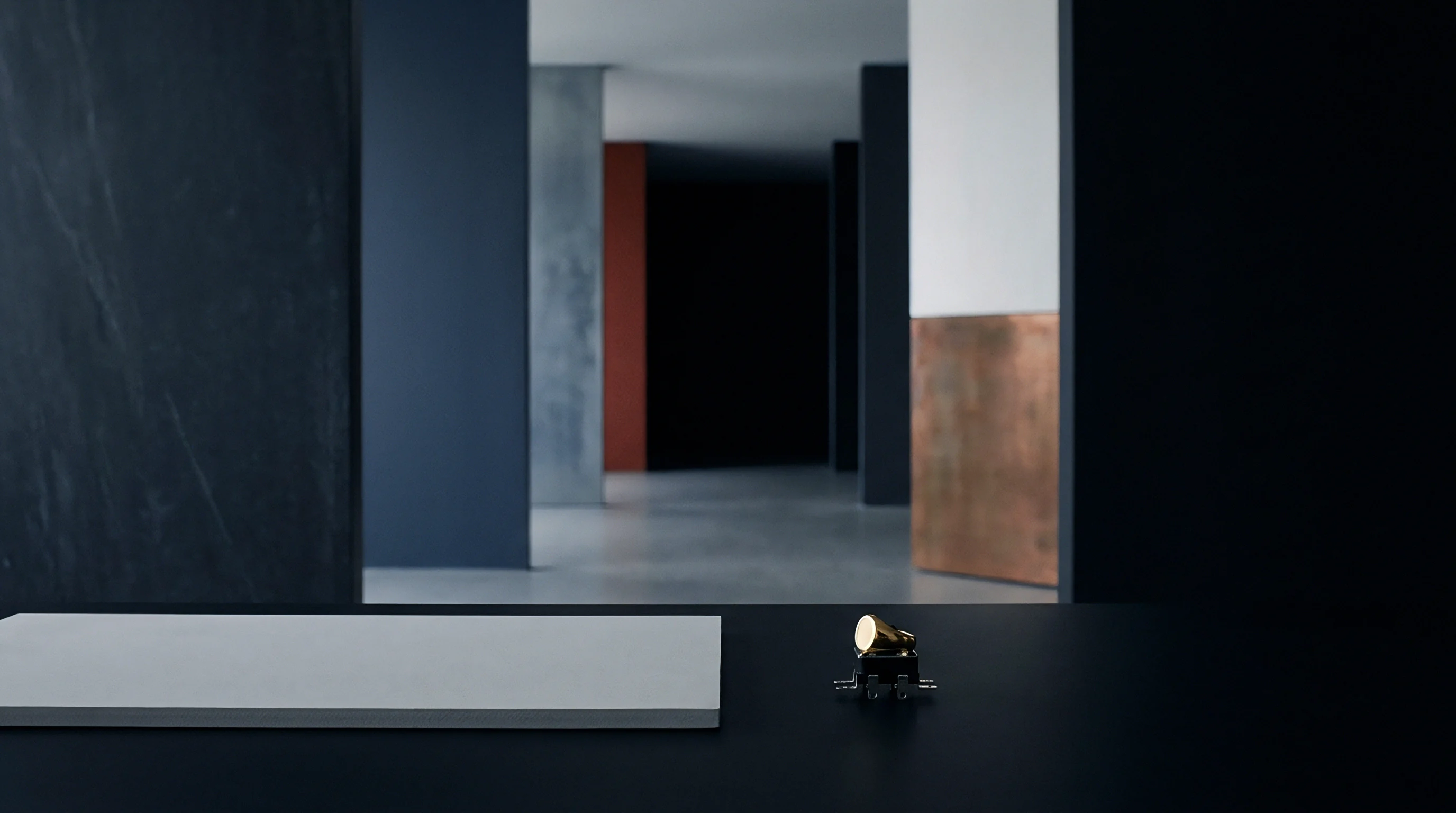 Black matte surfacing in this architectural render supports a miniature mechanical switch topped with a gold ring beside a white ceramic slab.